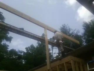 Carpenter setting a ridge beam over a new addition frame — Ice Dam Removal by Roofing Brothers in Pine Level