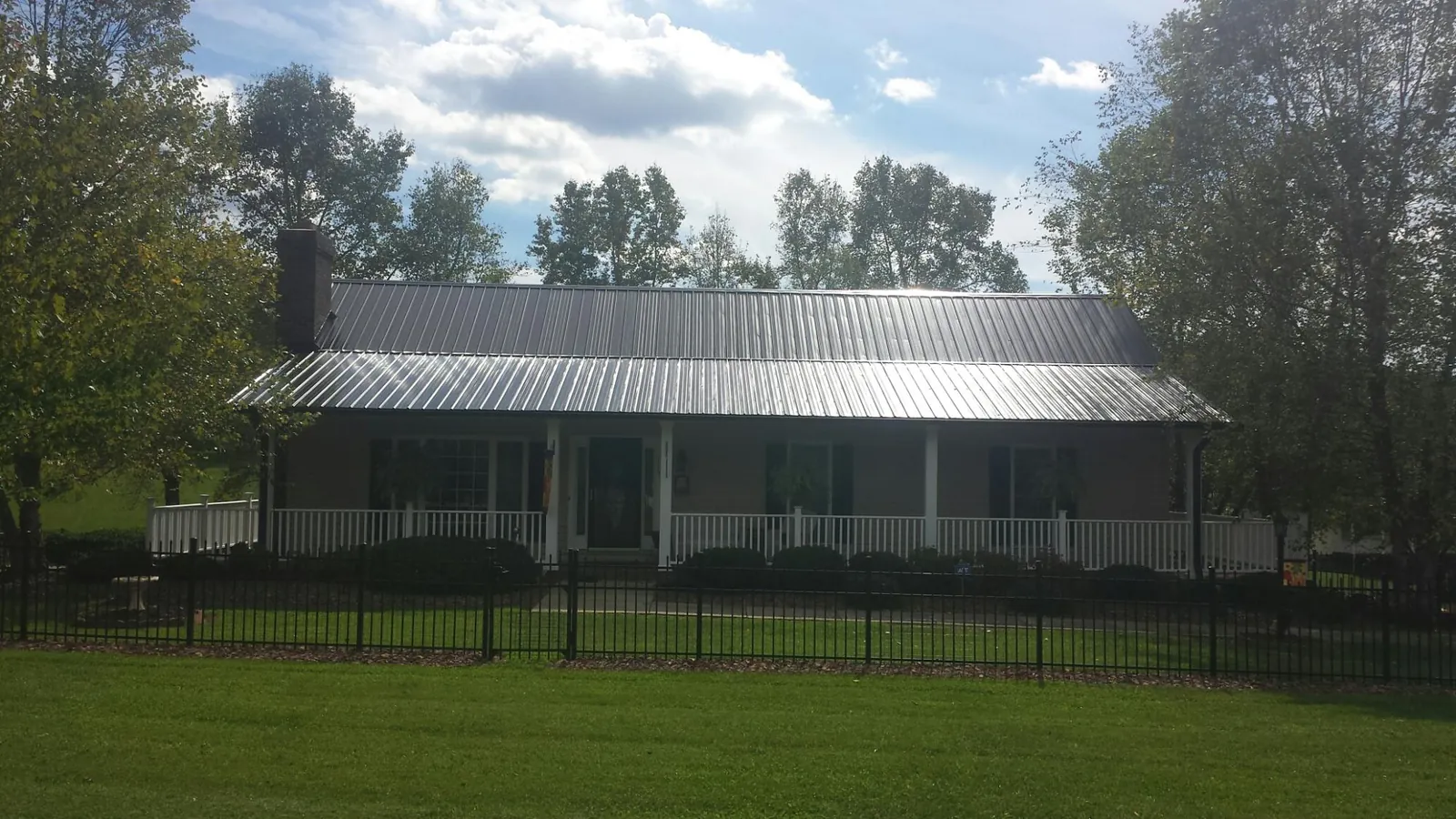 Gray metal roof on a brick ranch with a full width front porch — Gutter Guard Installation work by our crew in Pine Level