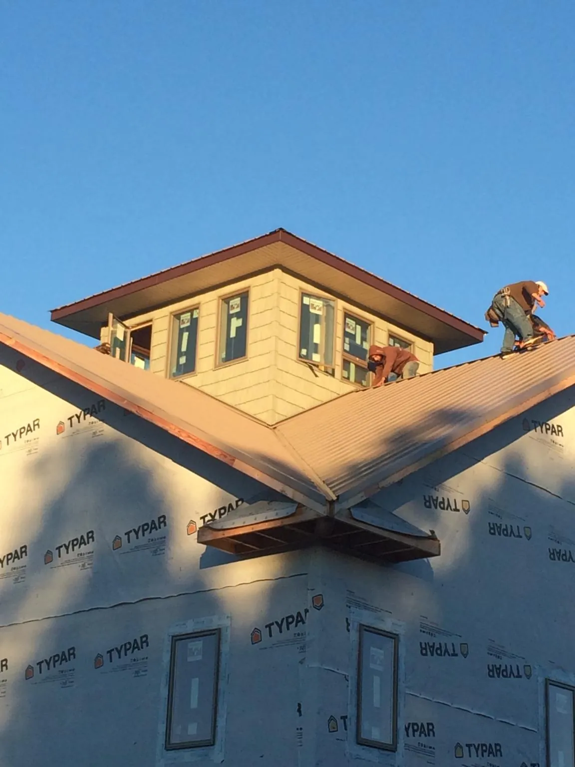 Roofers working around a rooftop cupola on a new metal roof at sunset — Roof Waterproofing in Pine Level by Roofing Brothers
